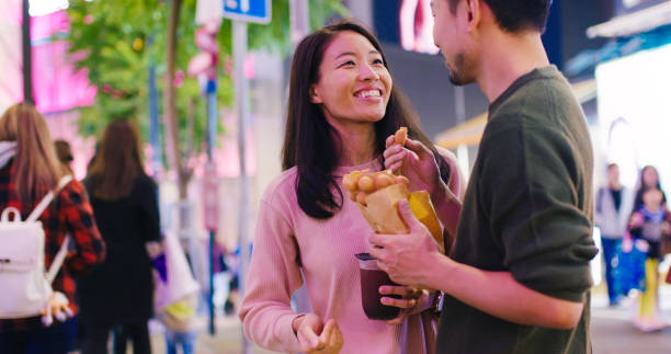 istock Young couple enjoying egg waffles and bubble tea outdoors at night 1202652033