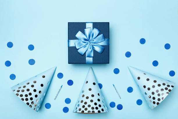 istock Birthday blue background composition with party gift present caps confetti candles top view flat lay 1202657266
