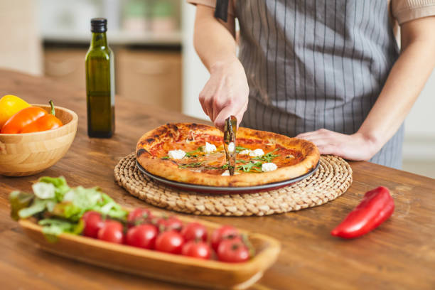 istock Woman cutting homemade pizza 1202664870