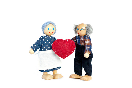 Dolls Elderly man and woman. Grandfather gives grandmother a heart a symbol of love and trust. Valentine's day, love. On white background.