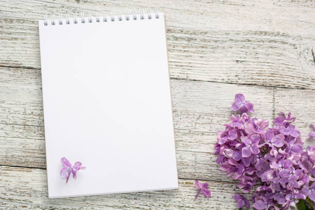 istock Clean notepad with spring lilac flowers on white wooden background 1202671813