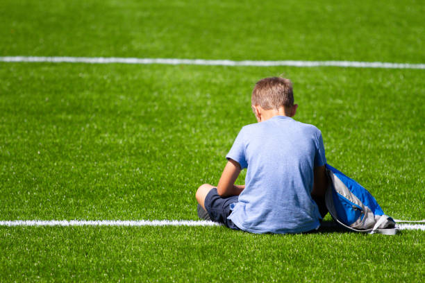 istock Sad alone boy with backpack sitting stadium outdoors 1202675194