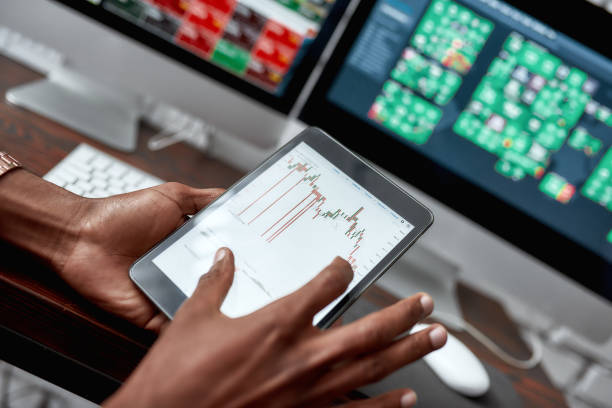 istock For the things you need. Close up shot of hands holding tablet pc. Trader is using touch screen tablet for analyzing stock market chart, while working in the office 1202675381