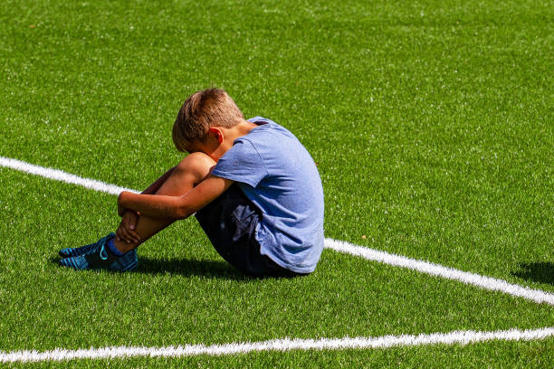 istock Sad disappointed boy sitting on the grass in stadium 1202675399