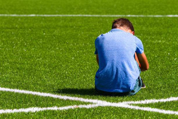 istock Sad disappointed boy sitting on the grass in stadium 1202675433