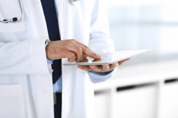 istock Doctor man using tablet computer for network research or virtual disease treatment, hands close-up. Perfect medical service in clinic. Modern medicine, medic data and healthcare concepts. Toned picture 1202676653