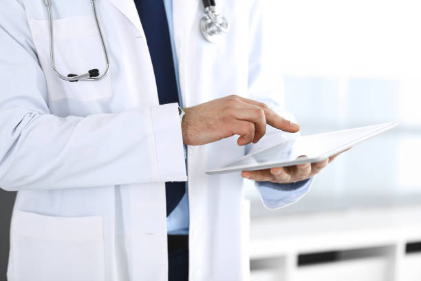 istock Doctor man using tablet computer for network research or virtual disease treatment, hands close-up. Perfect medical service in clinic. Modern medicine, medic data and healthcare concepts. Toned picture 1202676660