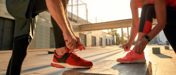 aktywny poranek. zbliżenie zdjęcia dwóch osób w sportowych ubraniach wiążących sznurowadła przed bieganiem razem na świeżym powietrzu - running jogging men shoe zdjęcia i obrazy z banku zdjęć