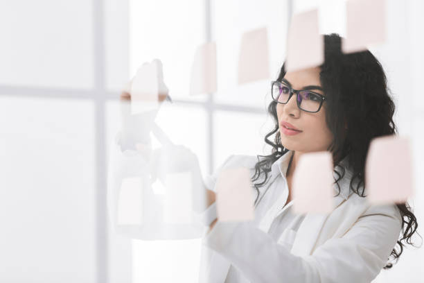 istock Hispanic manager writing on adhesive notes on glass wall 1202680515