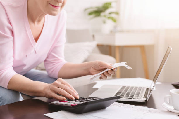 istock Senior lady counting bills with calculator at home 1202680619