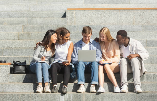 istock Students doing homework on laptop, sitting on stairs in city 1202682169