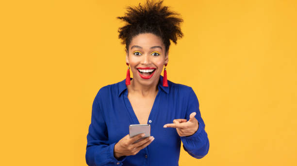 istock Amazed black woman pointing at mobile phone 1202682267