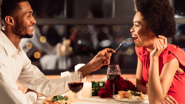 istock Couple Feeding Each Other Having Romantic Dinner In Restaurant, Panorama 1202683411