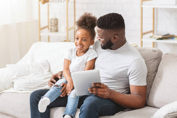 istock Black father and daughter using digital tablet at home 1202683698