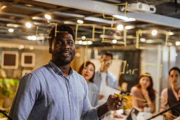 istock Black man writing on glass wall in the office 1202683739