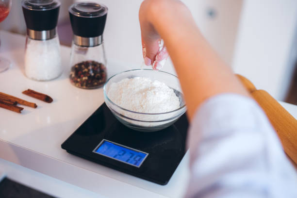 Measuring flour Young Caucasian woman measuring flour on skale in kitchen. POV view. kitchen scale stock pictures, royalty-free photos & images