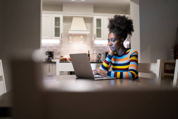 femme africain utilisant l'ordinateur portatif à la maison la nuit - e commerce internet e mail shopping photos et images de collection