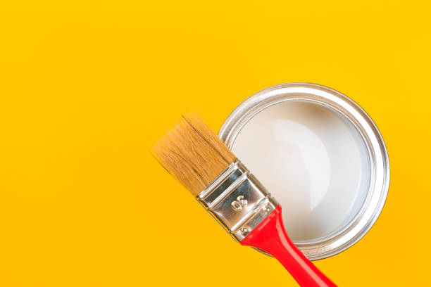 istock White Paint Can with Brush Top View On Yellow Background. 1202687063