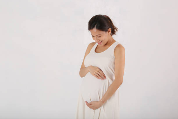 Young Asian pregnant woman expecting new child in white isolated background stock photo