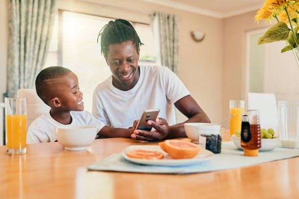 Dad, what is that? Cropped shot of a happy father and son bonding over breakfast and technology during a weekend at home carbohydrate food type photos stock pictures, royalty-free photos & images