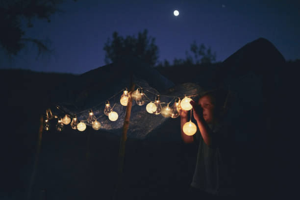 istock Kid making a small tent with candles and lampions in the backyard. 1202689609