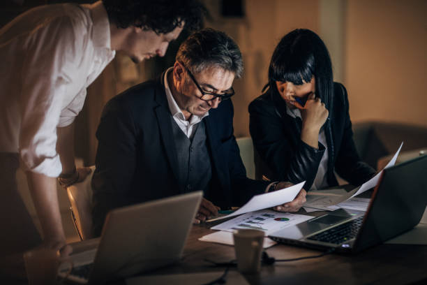 istock Three colleagues working late at night in office together 1202689987