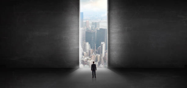 istock Businessman looking to a cityscape from a dark empty room 1202691693