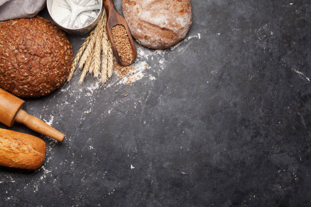 Various bread with wheat, flour and cooking utensils Various bread with wheat, flour and utensils on stone table. Homemade cooking concept. Top view flat lay with copy space baking bread stock pictures, royalty-free photos & images