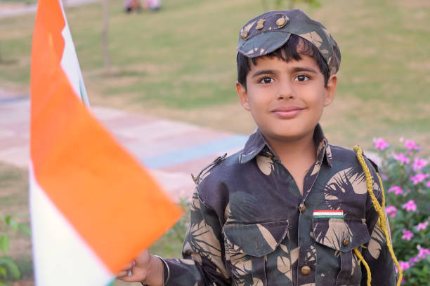 istock Elementary age child holding flag in hands wearing army uniform during independence day celebration event portrait outdoor in nature. 1202692106