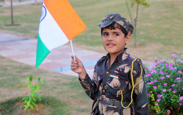 istock Elementary age child holding flag in hands wearing army uniform during independence day celebration event portrait outdoor in nature. 1202692109