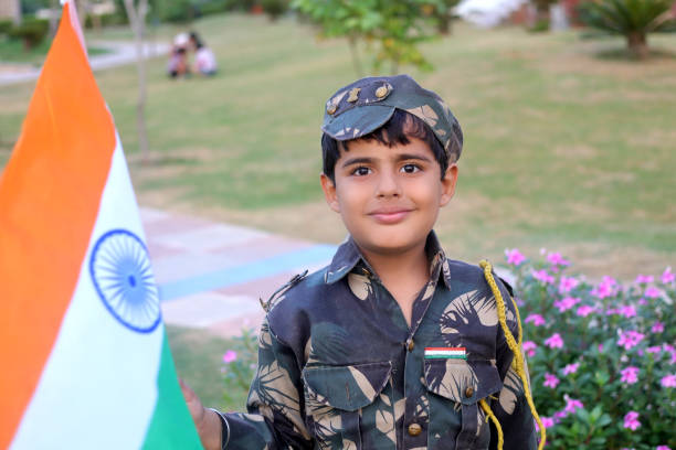 istock Elementary age child holding flag in hands wearing army uniform during independence day celebration event portrait outdoor in nature. 1202692114