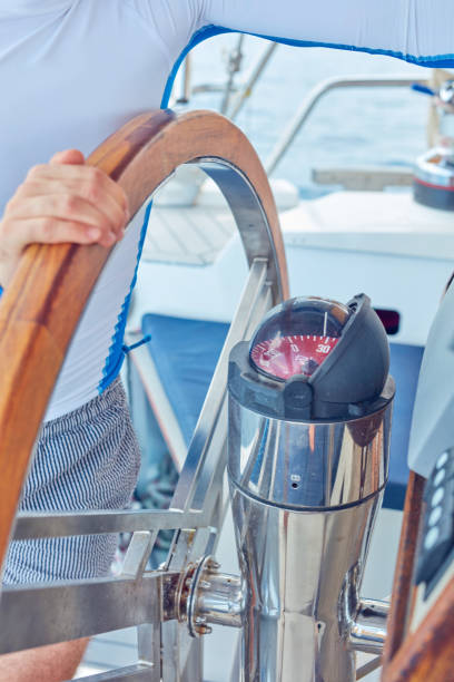 istock Sailor using wheel to steer rudder on a sailing boat. 1202692322
