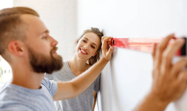 若い幸せなカップルは、自宅で壁を修復し、塗装しています - female house painter home decorator paintbrush ストックフォトと画像