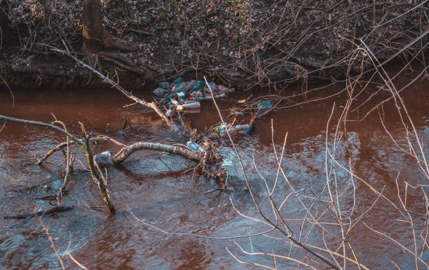 istock Water pollution with plastic bags in river. Orange water 1202693375
