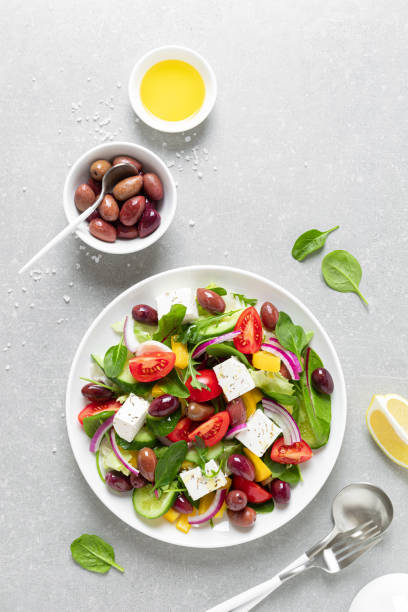 insalata greca con verdure, olive e chesse feta su un piatto bianco, vista dall'alto - greek culture salad olive feta cheese foto e immagini stock