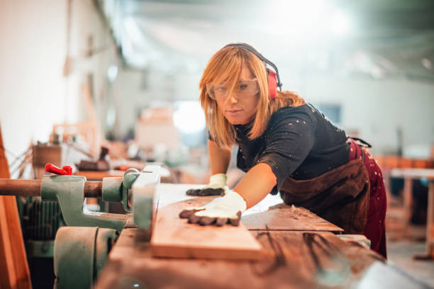 istock Blond female carpenter cutting a plank on a workbench 1202693763