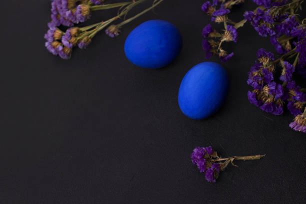 istock Classic blue Easter eggs on a black background with purple flowers. copy space 1202694576
