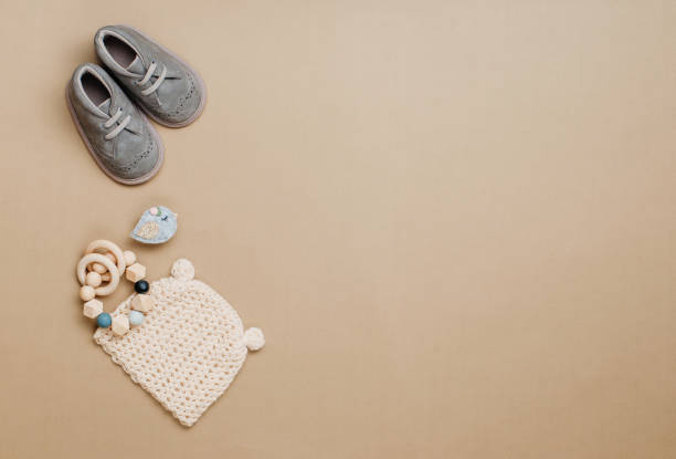 istock Baby wooden teether, knitted hat and shoes on beige background 1202695604