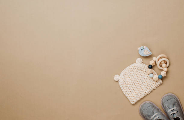 istock Wooden teether, knitted hat and shoes on beige background 1202695689