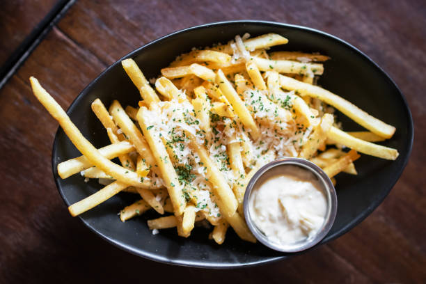 queijo e salsa batatas fritas em tigela preta na mesa de madeira. - gold potato - fotografias e filmes do acervo