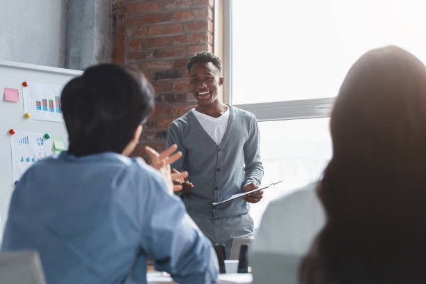istock Cheerful black employee talking to colleagues while presentation 1202697073