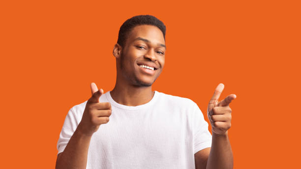 istock Excited black guy choosing you over orange background 1202697700