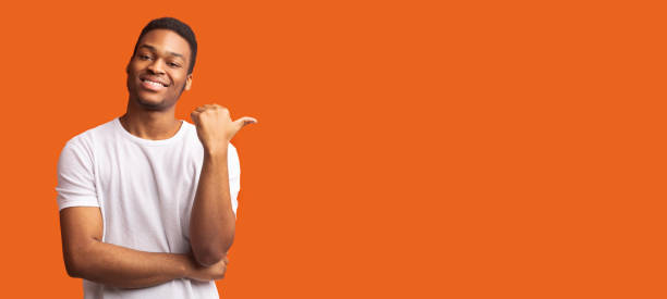 istock Young afro guy pointing at copy space with thumb up 1202698308