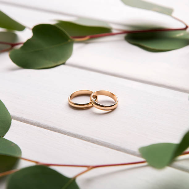 istock Creative composition of wedding rings and green leaves 1202698382
