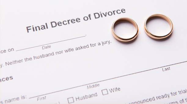 istock Two golden wedding rings on final divorce decree document 1202698567