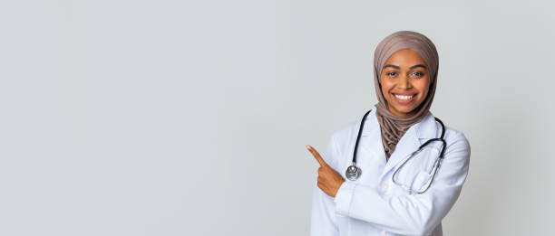istock Black Female Doctor In Headscarf Indicating Copy Space On Light Background 1202698599