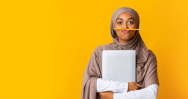 verspielte afro islamische mädchen posiert mit bleistift unter nase und laptop - nerd computer learning fun stock-fotos und bilder