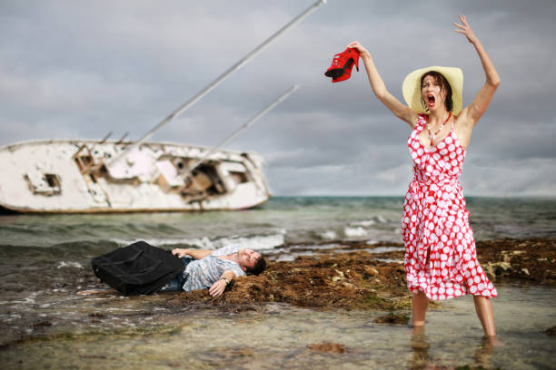 Crash yacht A man and a woman escaped from their sunken yacht. She is in nice red dress and holds red hills, and he cares about his black suitcase.Concept with humor. ship wreck shore storm stock pictures, royalty-free photos & images