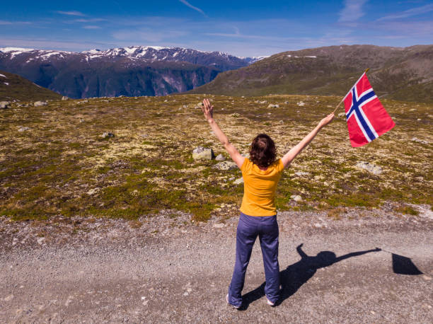 istock Tourist holds norwegian flag in mountains 1202699461