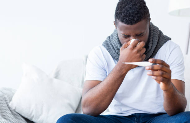 istock Sick african american guy holding thermometer, having fever 1202700393